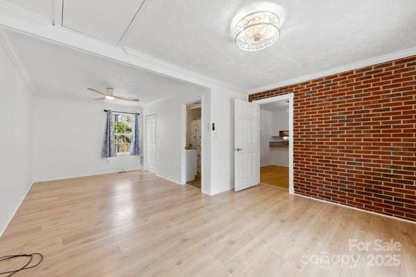 unfurnished room featuring brick wall, light wood finished floors, and crown molding