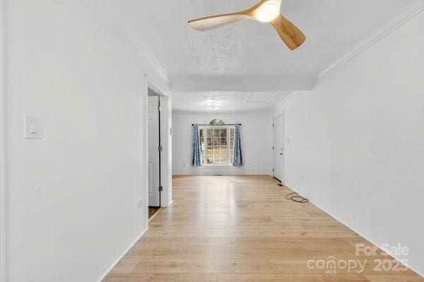 empty room featuring ornamental molding, light wood-style flooring, and a ceiling fan