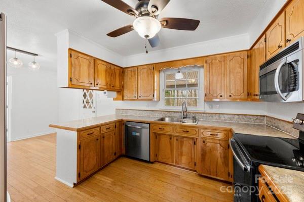 kitchen with a peninsula, light wood finished floors, stainless steel appliances, and a sink