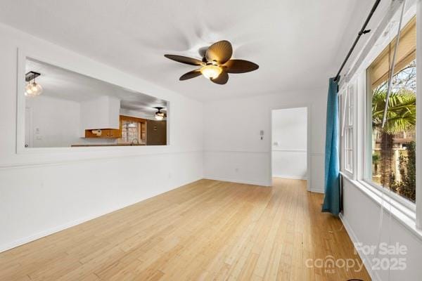 empty room featuring ceiling fan, wood finished floors, and baseboards