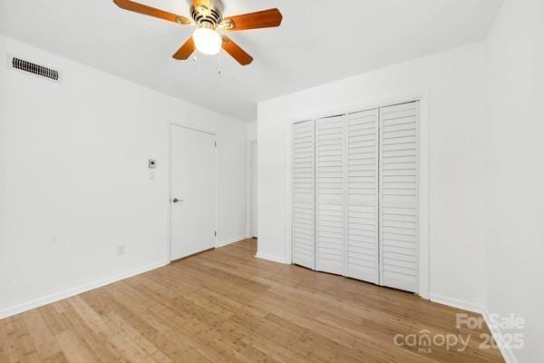 unfurnished bedroom with baseboards, a closet, visible vents, and wood finished floors