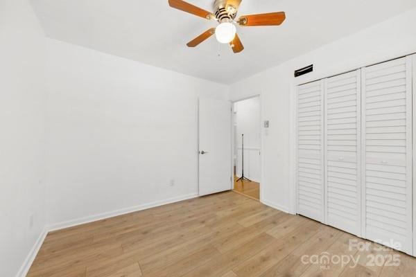 unfurnished bedroom featuring light wood finished floors, a closet, a ceiling fan, and baseboards