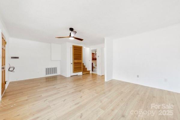 spare room with ceiling fan, stairway, light wood-type flooring, and visible vents