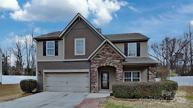 view of front facade featuring board and batten siding, fence, a garage, stone siding, and driveway