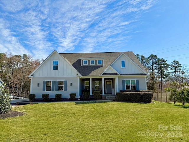 view of front of house featuring fence, a front lawn, board and batten siding, and roof with shingles