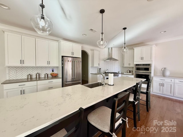 kitchen featuring arched walkways, visible vents, white cabinetry, wall chimney range hood, and high end appliances