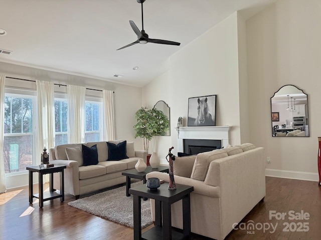 living room featuring high vaulted ceiling, dark wood-style flooring, a fireplace, a ceiling fan, and baseboards