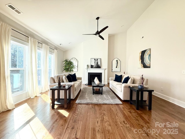 living room with dark wood-style floors, a fireplace with flush hearth, visible vents, and baseboards