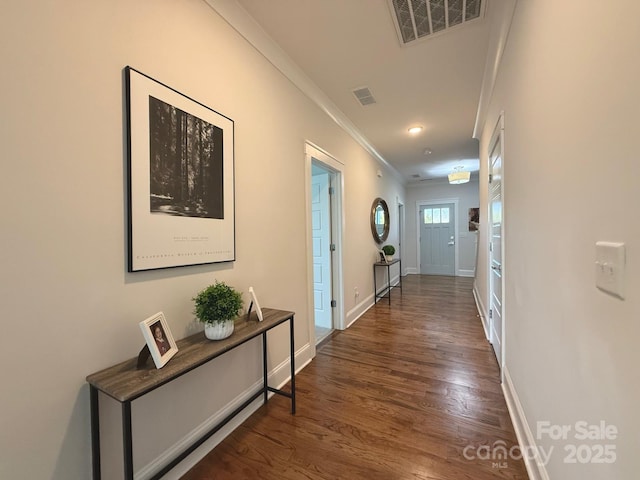 corridor with baseboards, visible vents, crown molding, and wood finished floors