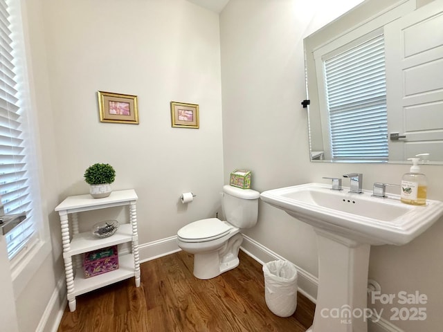 bathroom with toilet, baseboards, and wood finished floors