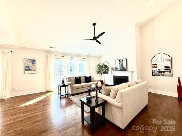 living room with visible vents, baseboards, dark wood finished floors, a ceiling fan, and a fireplace