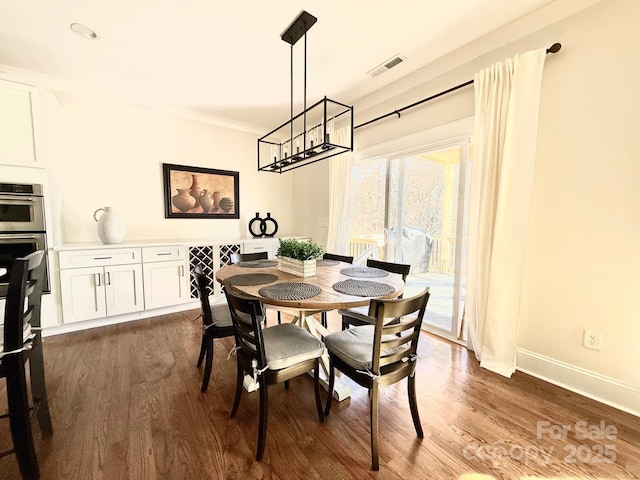 dining area featuring ornamental molding, dark wood-type flooring, visible vents, and baseboards