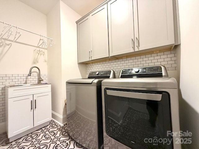 washroom featuring separate washer and dryer, a sink, baseboards, cabinet space, and tile patterned floors