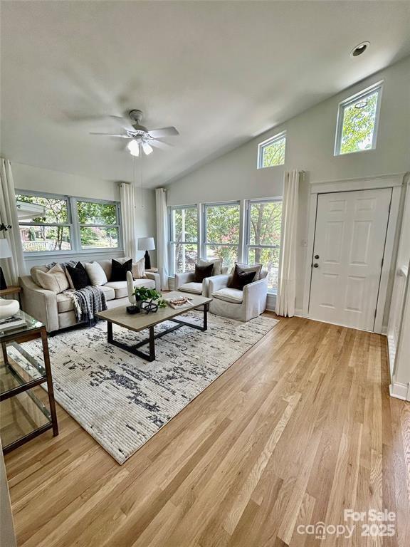 living room featuring light wood-type flooring, high vaulted ceiling, and a ceiling fan