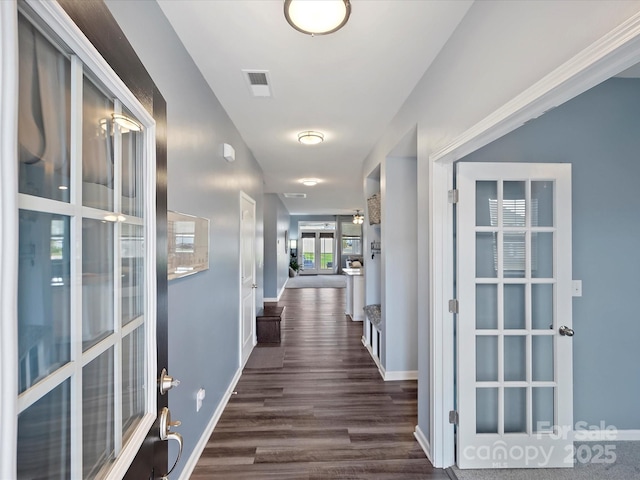 corridor with dark wood-style floors, visible vents, and baseboards