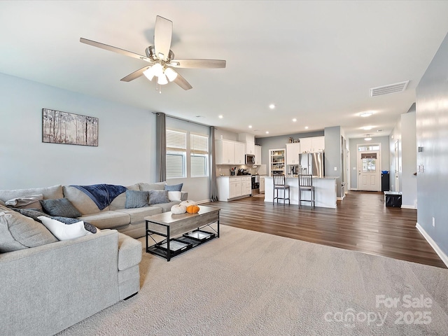 living area with dark wood-style floors, recessed lighting, visible vents, a ceiling fan, and baseboards