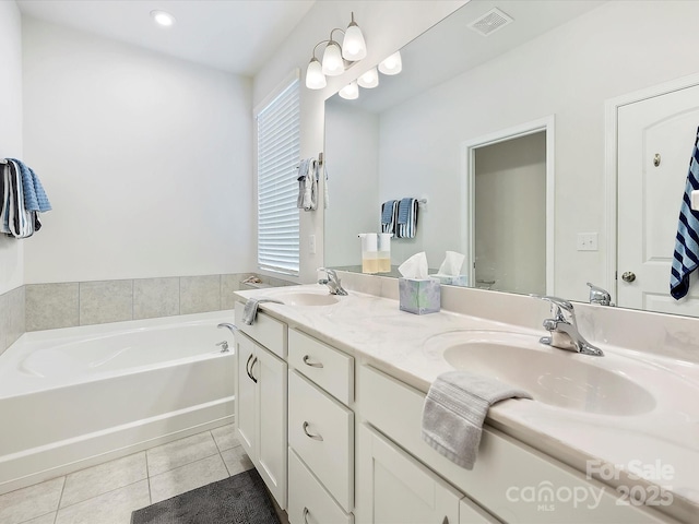 bathroom with double vanity, visible vents, tile patterned floors, a sink, and a bath