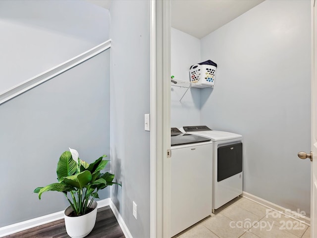 laundry room featuring laundry area, baseboards, washer and clothes dryer, and light tile patterned flooring