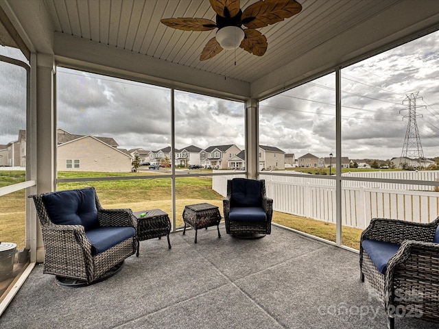 sunroom / solarium with ceiling fan, a wealth of natural light, wooden ceiling, and a residential view