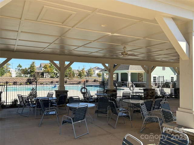 view of patio featuring ceiling fan, fence, and a community pool