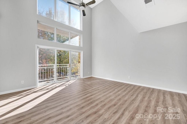 unfurnished living room featuring a ceiling fan, visible vents, baseboards, and wood finished floors