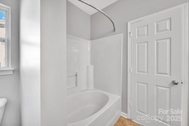 full bath with bathing tub / shower combination, tile patterned flooring, and toilet