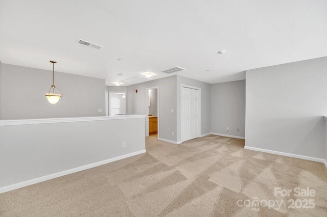 spare room with light carpet, baseboards, and visible vents