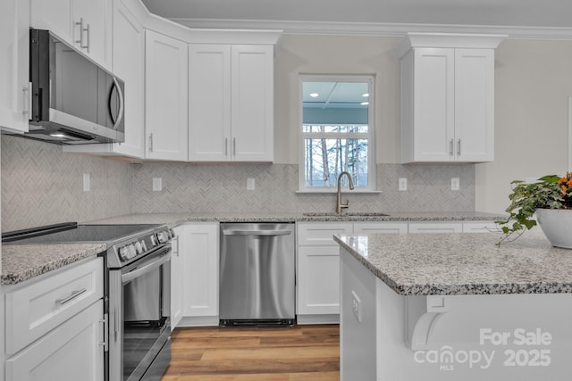 kitchen featuring crown molding, white cabinetry, stainless steel appliances, and a sink