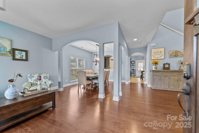 entryway with arched walkways, baseboards, and wood finished floors