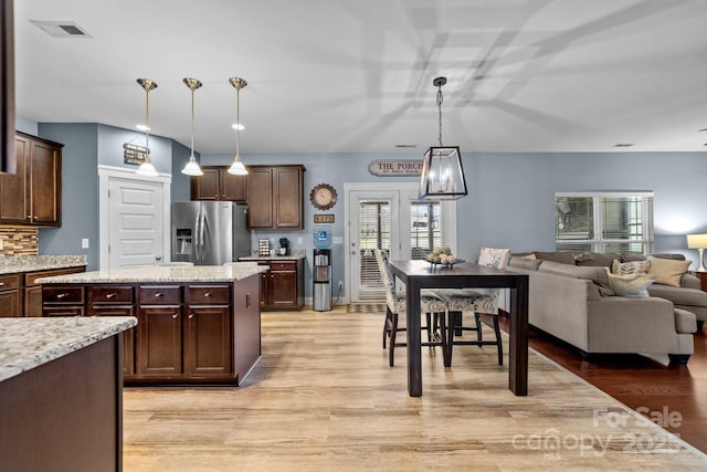 kitchen with stainless steel refrigerator with ice dispenser, light wood finished floors, visible vents, open floor plan, and dark brown cabinets