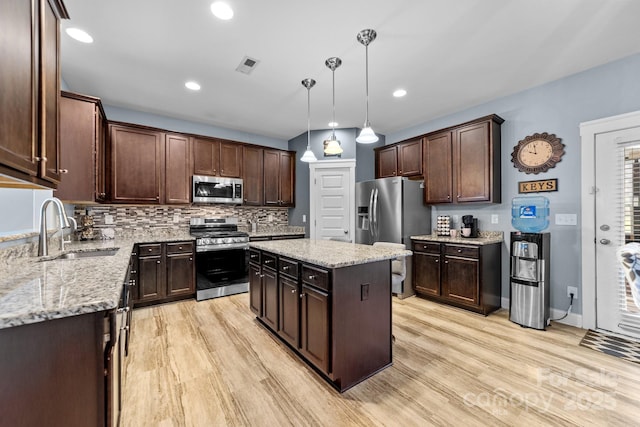 kitchen with stainless steel appliances, a sink, visible vents, light wood-style floors, and dark brown cabinets