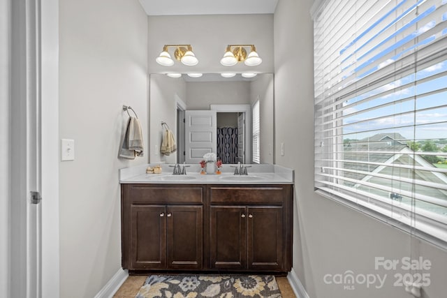 bathroom with double vanity, a sink, and baseboards