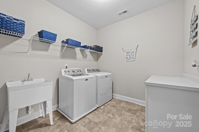 laundry area with laundry area, baseboards, visible vents, washer and clothes dryer, and a sink