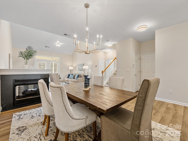 dining space featuring visible vents, a multi sided fireplace, light wood-style floors, and stairs