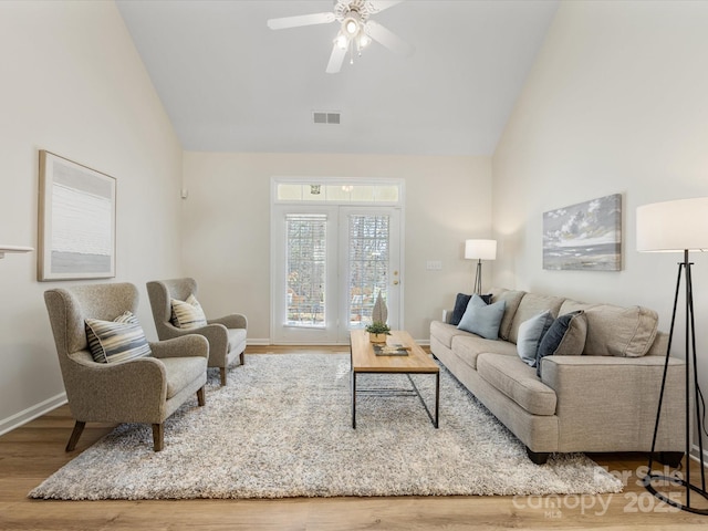 living room with visible vents, high vaulted ceiling, baseboards, and wood finished floors