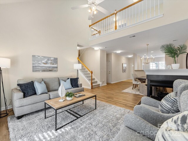 living area featuring visible vents, wood finished floors, stairway, a high ceiling, and baseboards