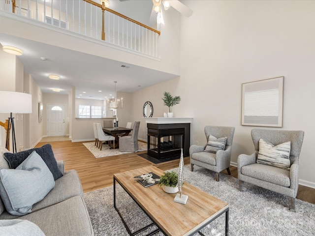 living room with visible vents, wood finished floors, baseboards, and a multi sided fireplace