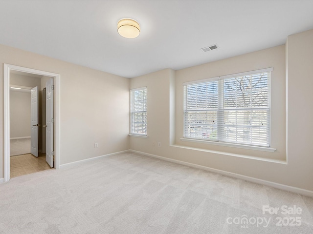 carpeted spare room featuring visible vents and baseboards