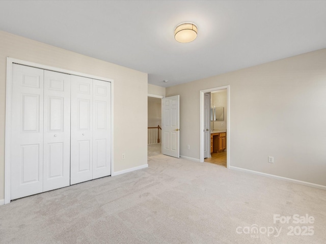 unfurnished bedroom with carpet flooring, baseboards, a closet, and connected bathroom