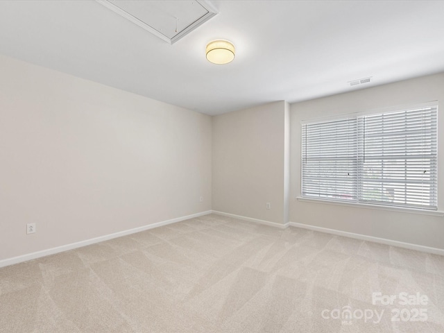 empty room featuring light carpet, visible vents, attic access, and baseboards