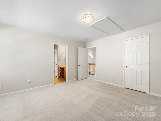 unfurnished bedroom featuring attic access, connected bathroom, baseboards, and light carpet