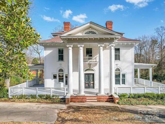 greek revival house featuring a balcony, a chimney, a porch, and french doors