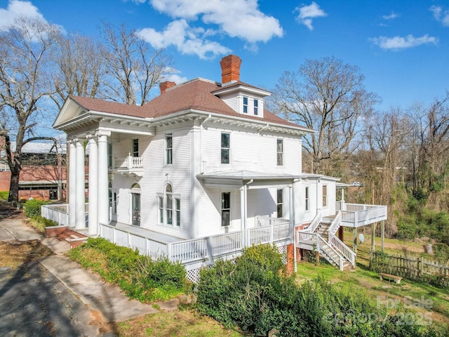 view of property exterior with a porch, a chimney, and stairway