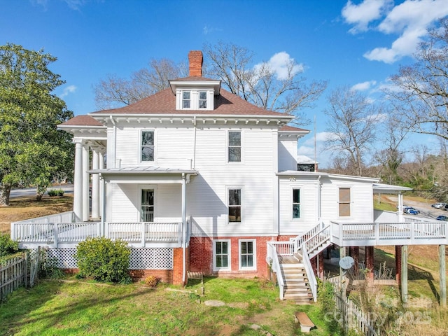 back of property featuring covered porch, fence, a yard, stairway, and a chimney