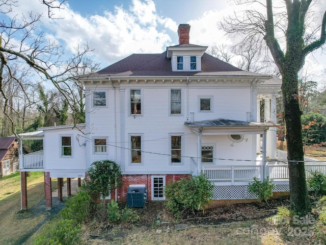 back of house featuring a chimney, central AC unit, and a porch