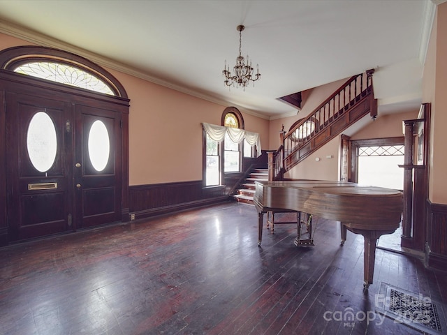 entryway featuring dark wood-type flooring, a wainscoted wall, a notable chandelier, and stairs