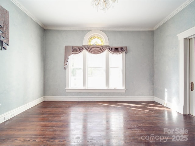 spare room with an inviting chandelier, baseboards, visible vents, and wood finished floors