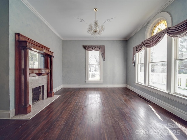 unfurnished living room featuring a fireplace with raised hearth, hardwood / wood-style flooring, visible vents, baseboards, and an inviting chandelier