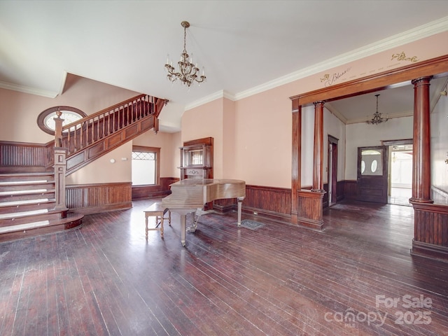 interior space featuring wainscoting, wood-type flooring, stairs, ornate columns, and a notable chandelier