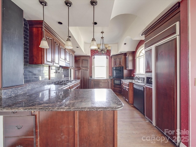 kitchen with stainless steel appliances, a peninsula, backsplash, light wood finished floors, and pendant lighting